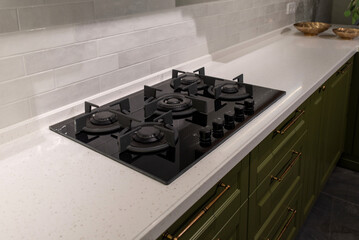 Black glass gas stove cooker on stone countertop.