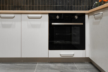 Black built in electric oven in a white kitchen, front view