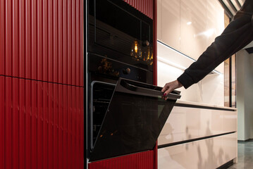 A woman opens the glass door of a built-in kitchen oven