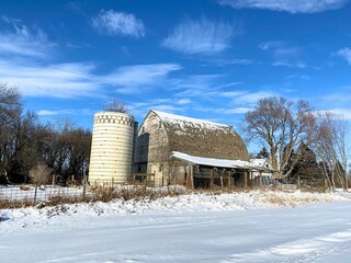 A perfectly blue sky contrasts this wood barn and the white snow cover