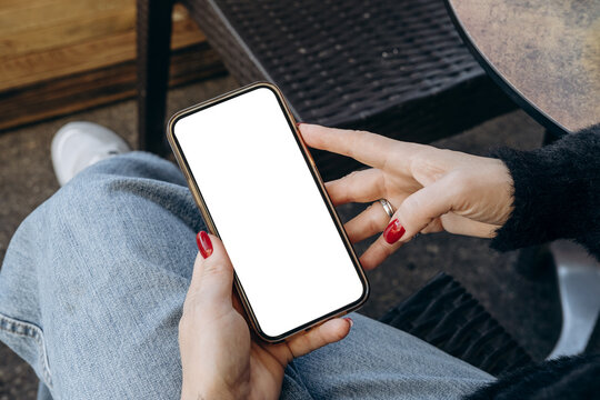 Mockup woman's hand holding using smart phone with white blank screen POV at coffee shop, mobile app design and advertising, online marketing