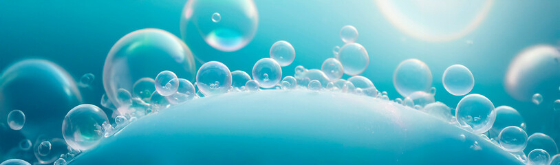 A macro photograph of translucent bubbles in various sizes, creating a dreamy atmosphere. Set against a soft blue and teal background, the glossy bubbles reflect light, enhancing tranquility.