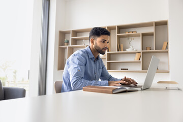 Serious Arabian office employee working on project at desk, correspond to client, typing e-mail,...