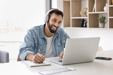 Smiling Hispanic man take part in online class using laptop and videocall application, enjoying...