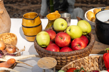 Green and red apples in a rustic wicker basket on a laid table