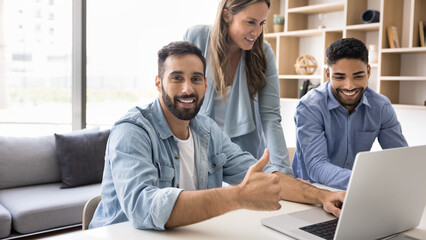 Latin man showing thumbs-up, gesture of approval or satisfaction with successful project progress, confirmation of good result or outcome in their teamwork, achievement, shared success, job well done