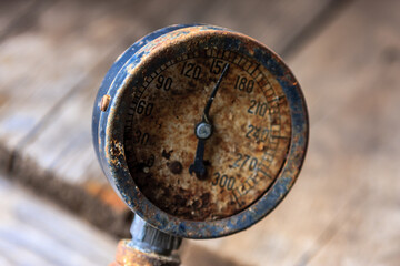 A rusted old pressure gauge with a black face and a white background