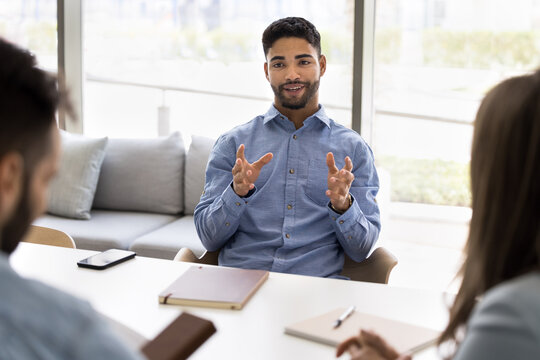Businessman, team leader explaining point of view, presenting new idea seated at table with colleagues, planning strategy for business and sales growth. Meeting of financial advisor and bank clients