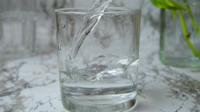 Closeup of tap water poured into glass on marble clean white background potos plant. Purity, rebirth, nature, health