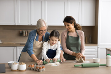 Family recipe. Intergenerational family older grandma young mum little child school age daughter...