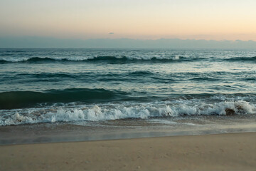 Tranquil ocean waves meet the shore at dusk.