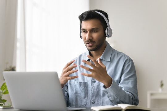 Video call conversation. Confident young male in digital headset talk to customer using notebook webcam give distant professional consultation support client online teach students in virtual classroom