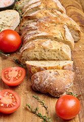 Sliced ​​baguette and red cherry tomatoes on a wooden board