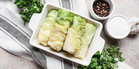 Baking dish with uncooked cabbage rolls on table