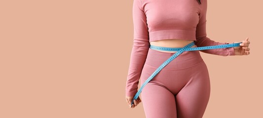 Young sporty woman measuring her waist on beige background with space for text. Weight loss concept