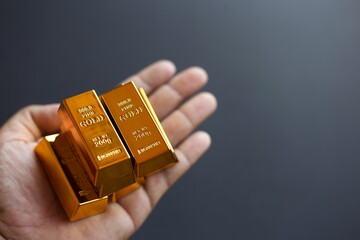 Hand holding gold bars on black background