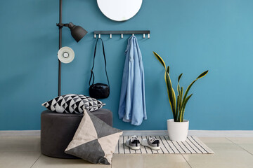 Interior of stylish hall with rack, pouf and lamp
