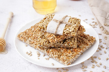 Plate with tasty kozinaki and jar of honey on white background