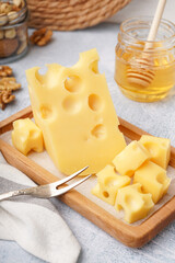 Board with pieces of Swiss cheese and honey on white table