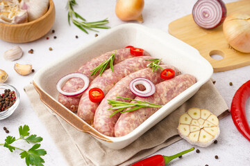 Baking dish with raw homemade sausages on light background