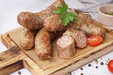 Wooden board of tasty homemade sausages on light background