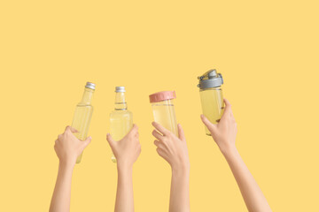 Women holding bottles with clean water on yellow background