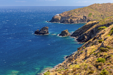 Cala Nans lighthouse on a rocky coastline on a sunny day, Cadaques, Spain