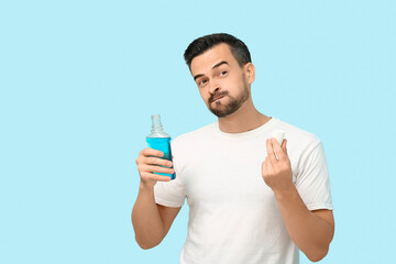 Handsome man with mouth rinse on blue background