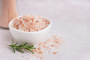 Bowl of Himalayan pink salt and rosemary on white background