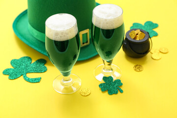 Glasses of beer with clover, coins and leprechaun hat on yellow background. St. Patrick's Day...