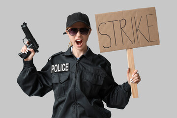 Protesting female police officer holding handgun placard with text STRIKE on grey background