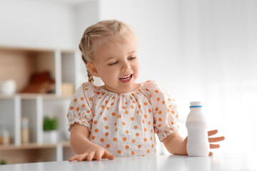 Happy little girl with bottle of yogurt at home