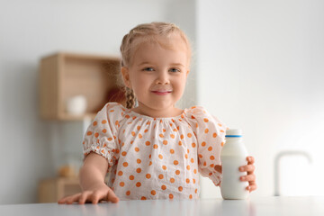 Cute little girl with bottle of yogurt at home