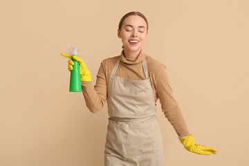 Young woman with spray bottle on beige background