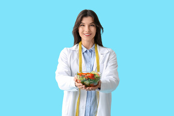 Female nutritionist with healthy food on blue background
