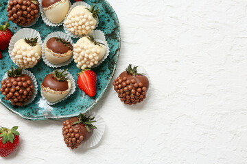 Plate with chocolate covered strawberries and fresh berries on white background