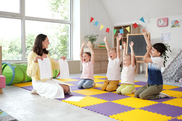 Little children with nursery teacher studying letters in kindergarten