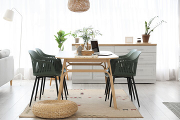 Pouf, chairs and table near window in interior of stylish dining room