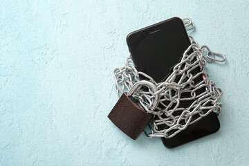 Modern mobile phone tied with chain and padlock on light background