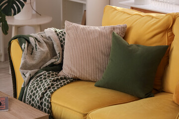 Comfortable yellow sofa with pillows in room, closeup