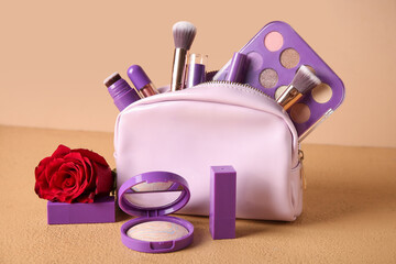 Cosmetic bag with makeup products and red rose on beige background. Valentine's day celebration
