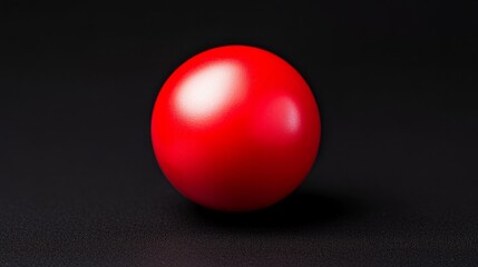 A glossy red ball rests against a dark background, showcasing a vibrant color contrast and smooth texture.