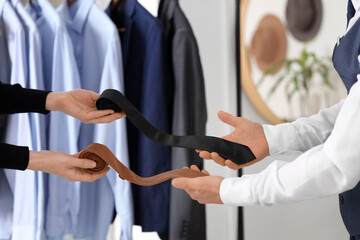 Seller and customer with neckties in boutique, closeup