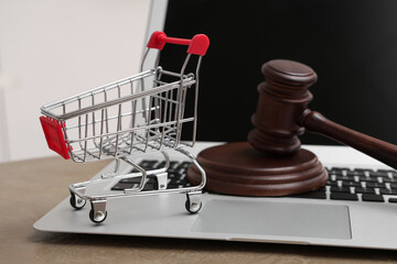 Shopping cart with auction gavel and laptop on table, closeup