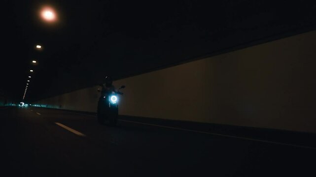 Rolling shot of a biker riding a naked motorcycle in a tunnel. Perfect for travel, motorsports, and road trip themes