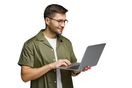 Man wearing glasses smiles while using a laptop and standing indoors in a modern environment