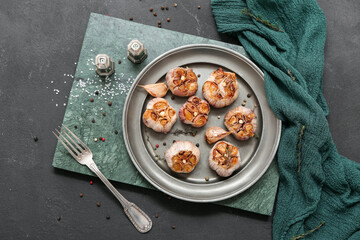 Plate with baked garlic, peppercorns and thyme on black background