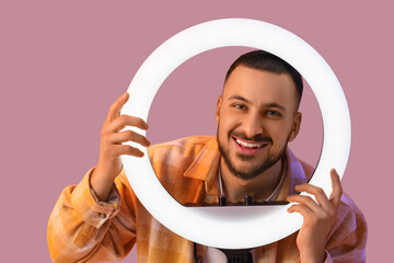 Young man with ring light on color background, closeup