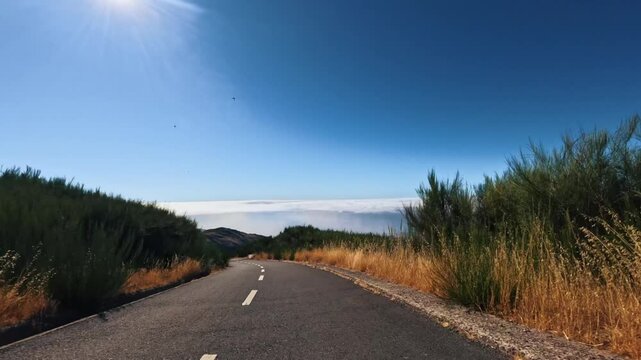 POV shot of a car driving on a scenic empty mountain road above the clouds. Establishing plate driving along Madeira island during daytime