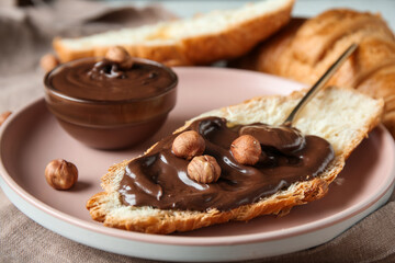 Plate of sweet croissant with chocolate spread and hazelnuts, closeup